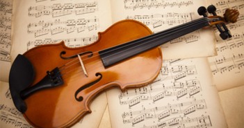 ImprendiNews – Musica e business – Un violino è appoggiato su un letto di spartiti