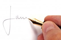 ImprendiNews – Una mano maschile firma con la stilografica mentre sul web fa la firma digitale