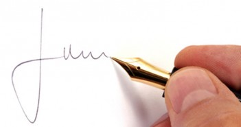 ImprendiNews – Una mano maschile firma con la stilografica mentre sul web fa la firma digitale